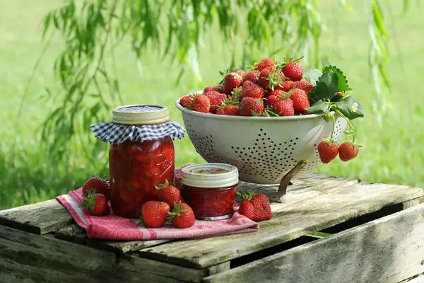 Pots de confiture de fraises et fraises fraîches sur une caisse en bois