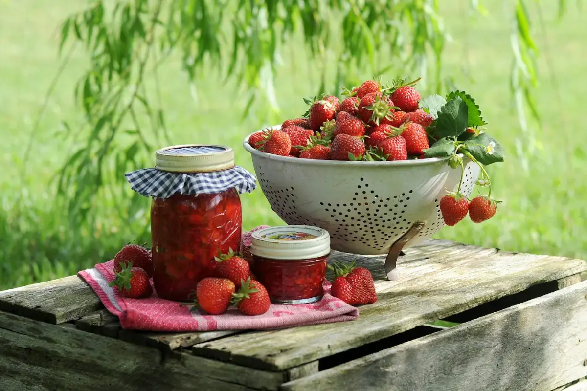Pots de confiture de fraises et fraises fraîches sur une caisse en bois
