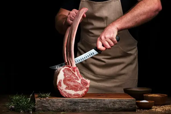 Boucher découpant une côte de bœuf sur un billot